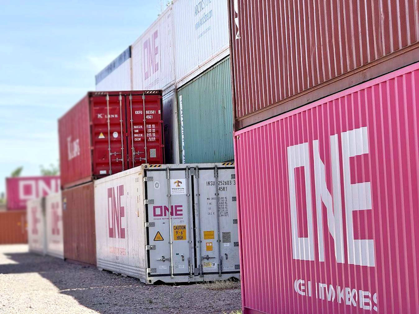Fila de contenedores apilados en terminal, con unidades ONE en primer plano
